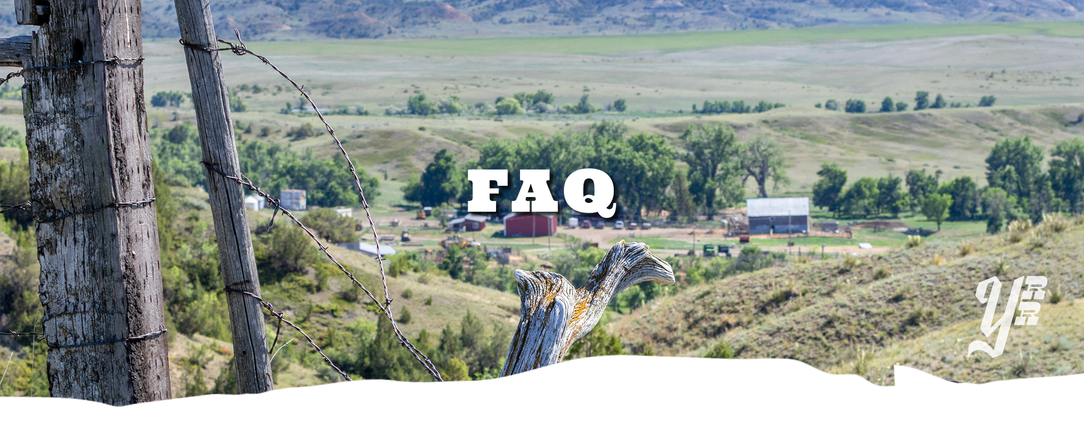 Barbed wire fence with 'FAQ' text in a rural Montana scenic landscape.