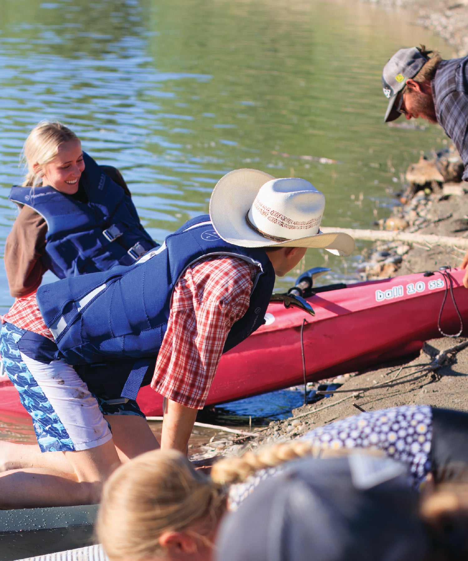 People preparing for kayaking on the Yellowstone River with one person wearing a cowboy hat.