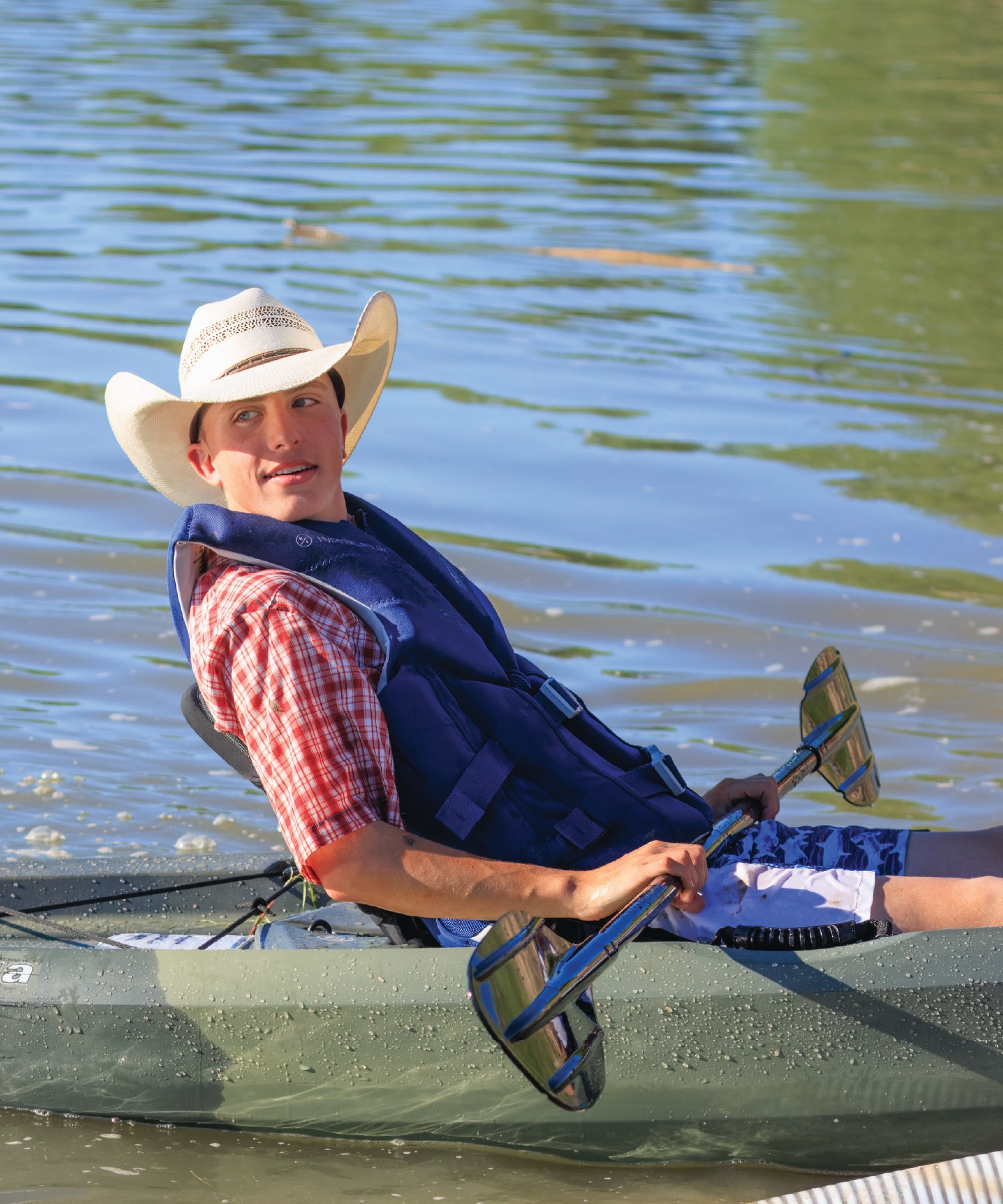 Man in a kayak wearing a cowboy hat and life jacket on calm water in the Yellowstone River