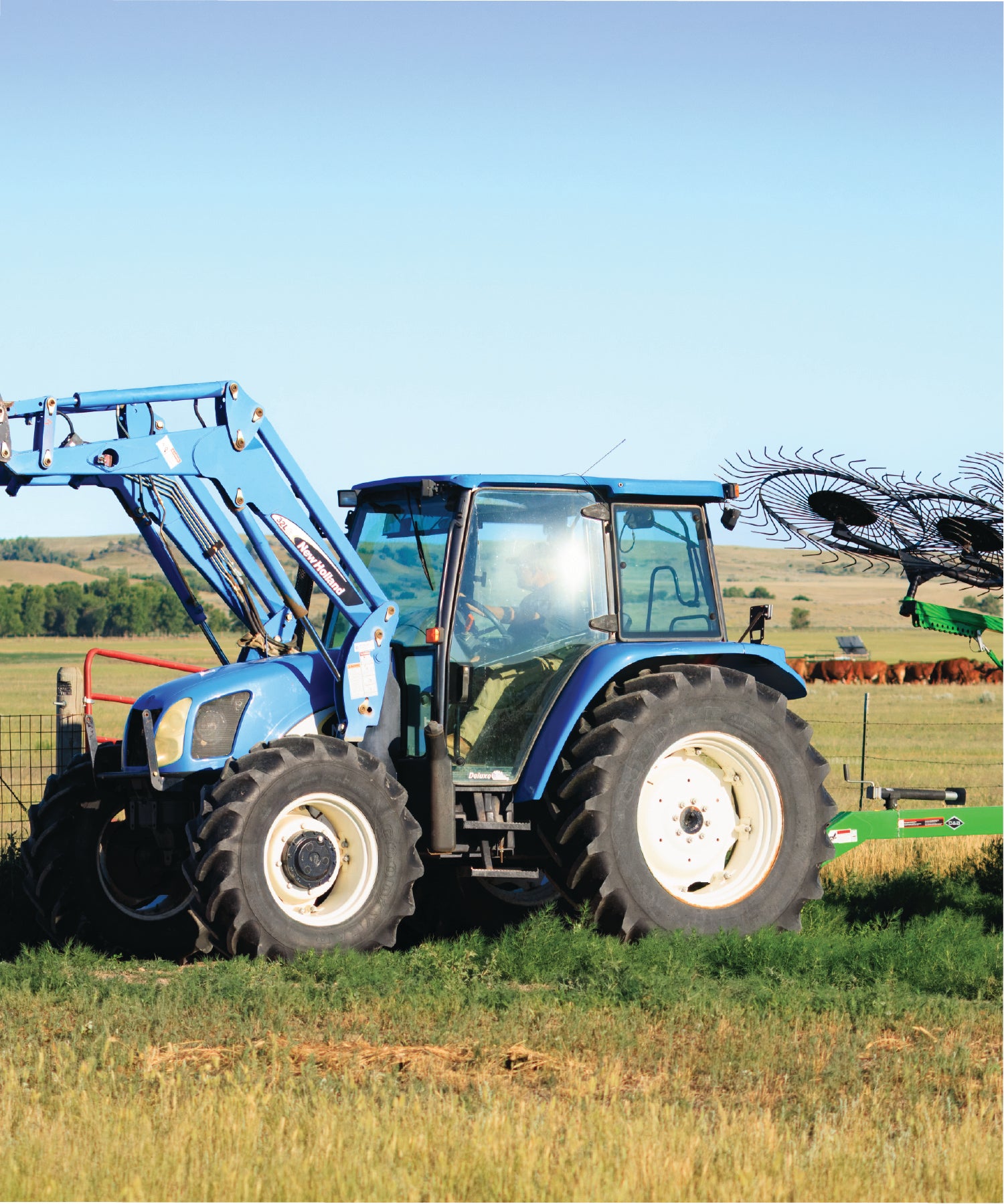 Blue tractor in a field with a clear sky