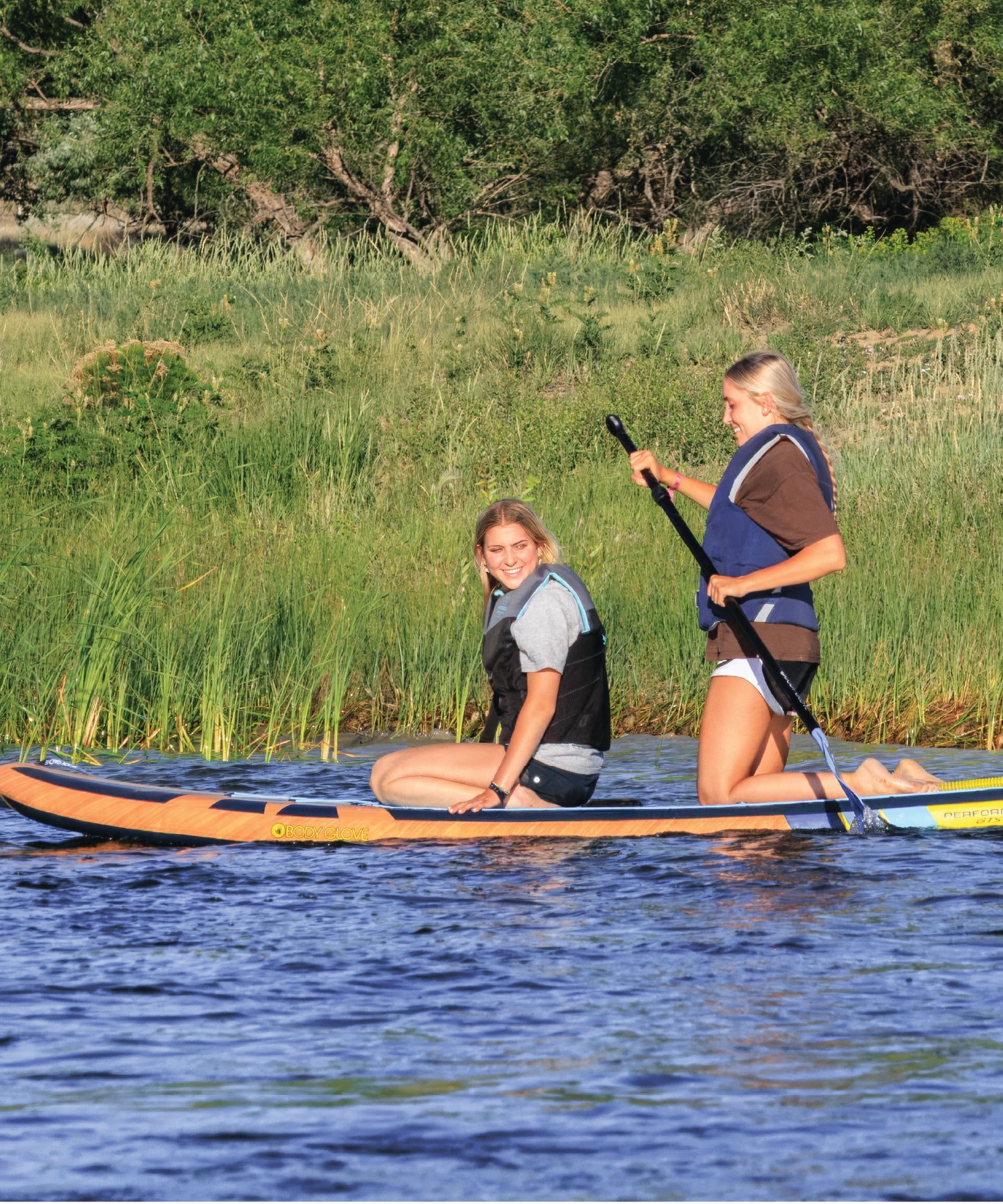 Two people on a paddleboard in the scenic Yellowstone River while smiling. 
