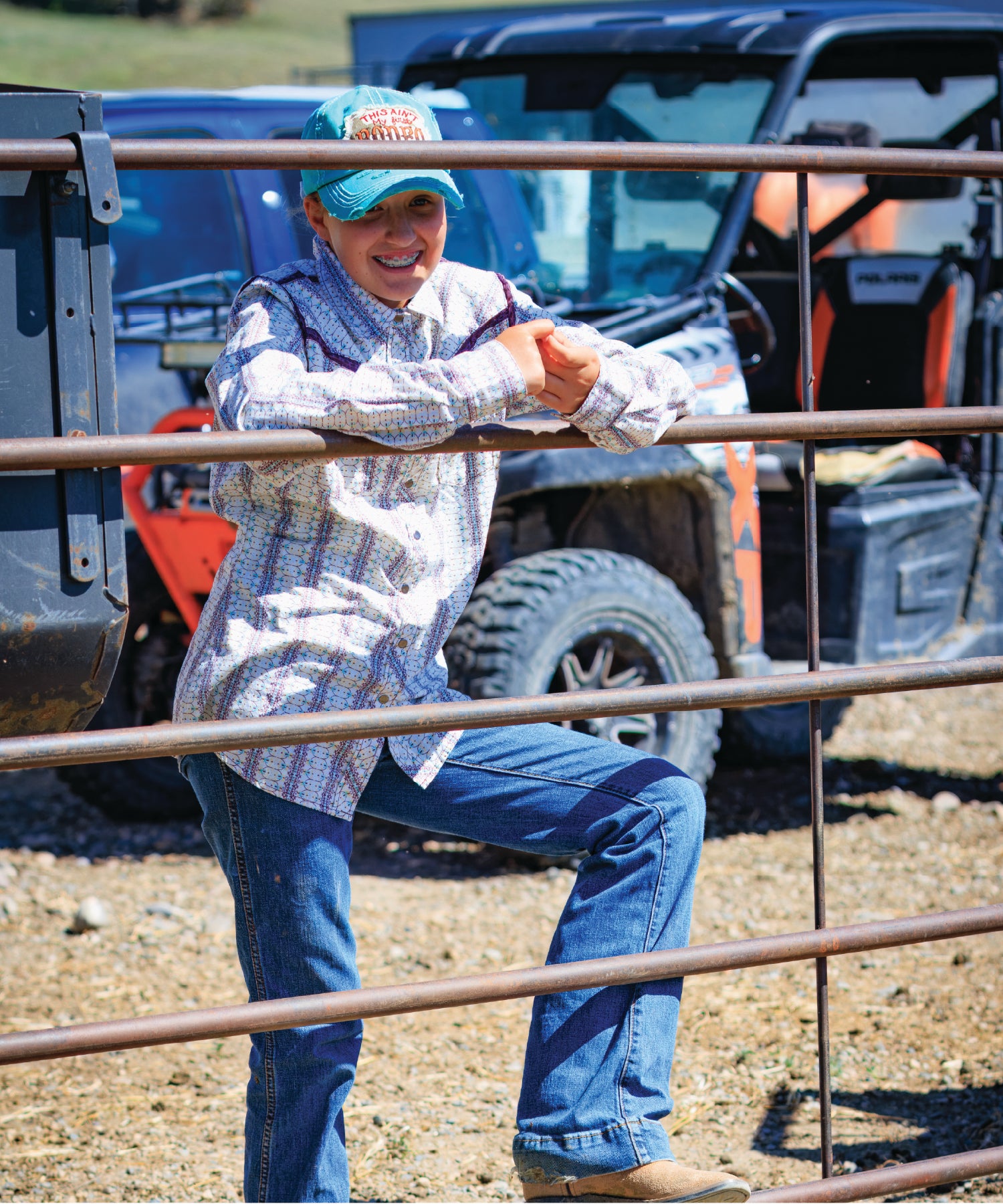Person leaning on a metal fence with off-road vehicles in the background