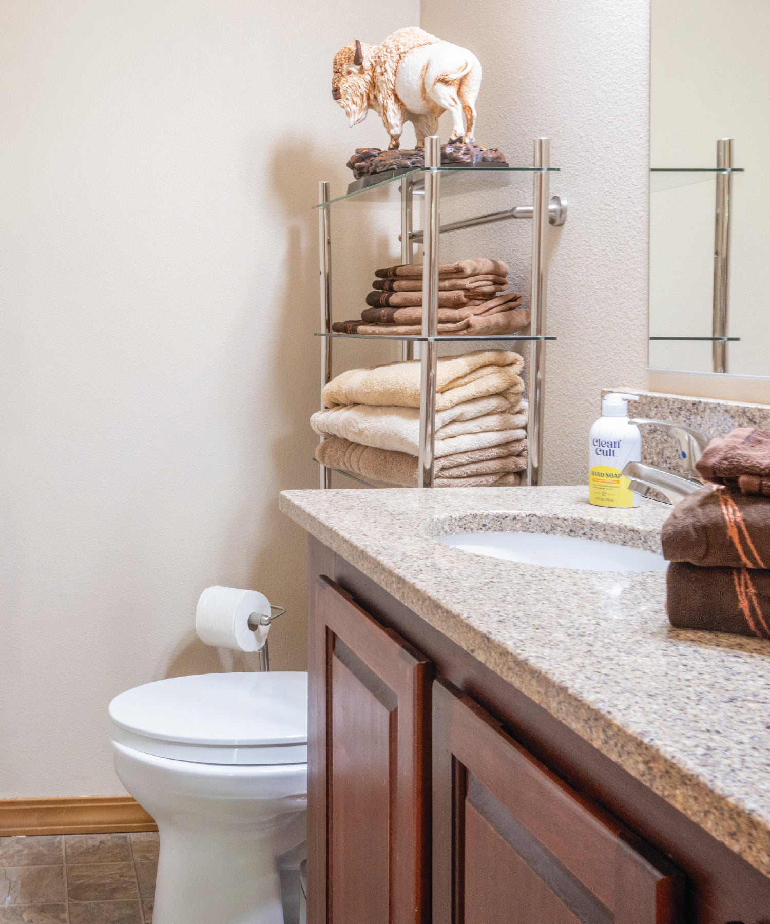 Bathroom with sink, towels, and a shelf with decorative items.