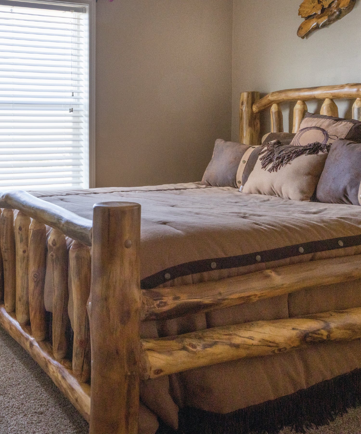 Wooden bed with bedding in a rustic room with a window and wall decor.