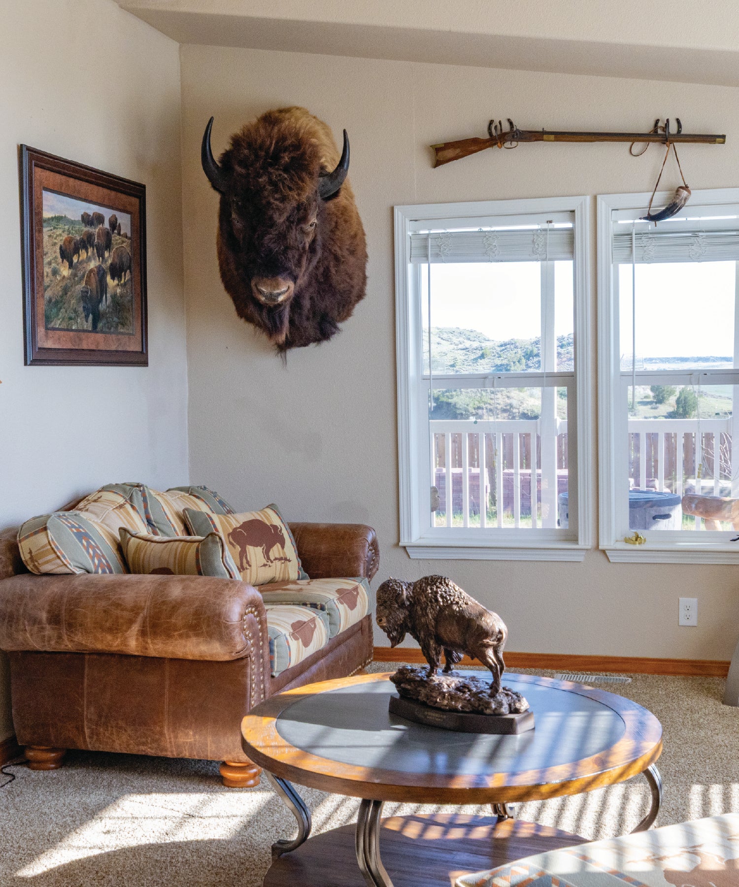 Living room with a mounted bison head on the wall, a couch, and a table with a bison statue.