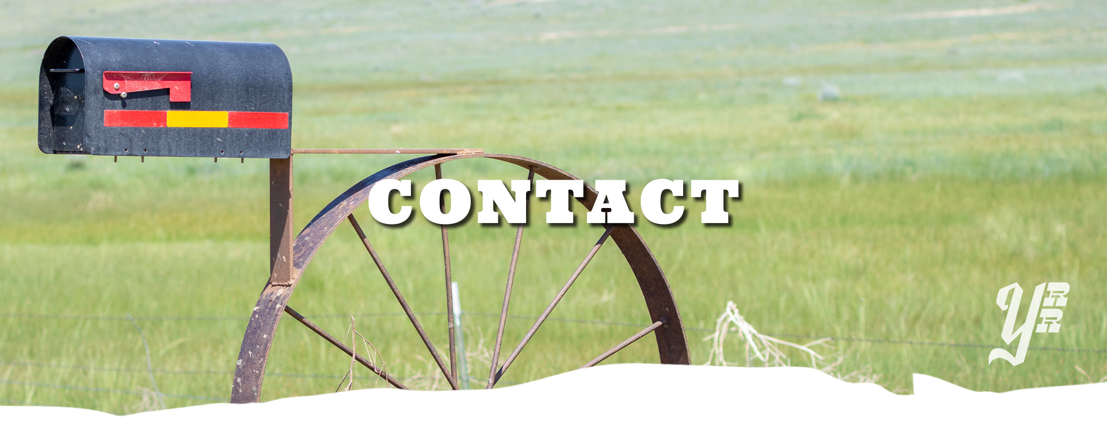 Mailbox with a 'contact' overlay and a wheel in front of a green field