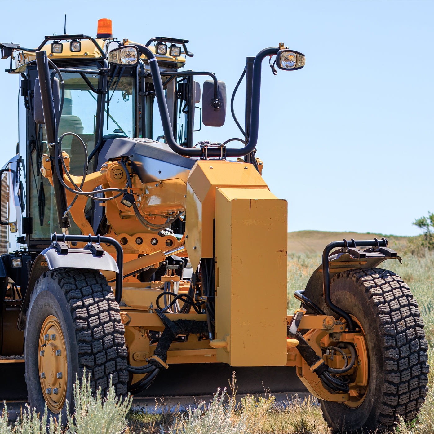 Yellow tractor vehicle on a grassy field with a clear blue sky.