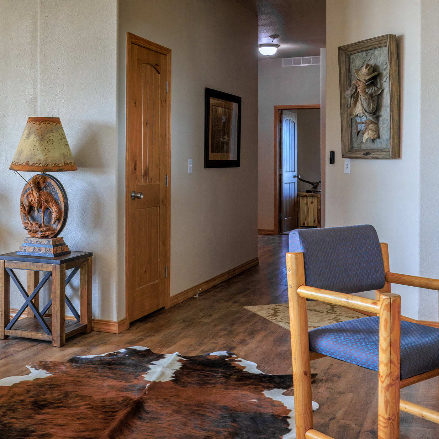 Narrow hallway with wooden chair, lamp, and cowhide rug