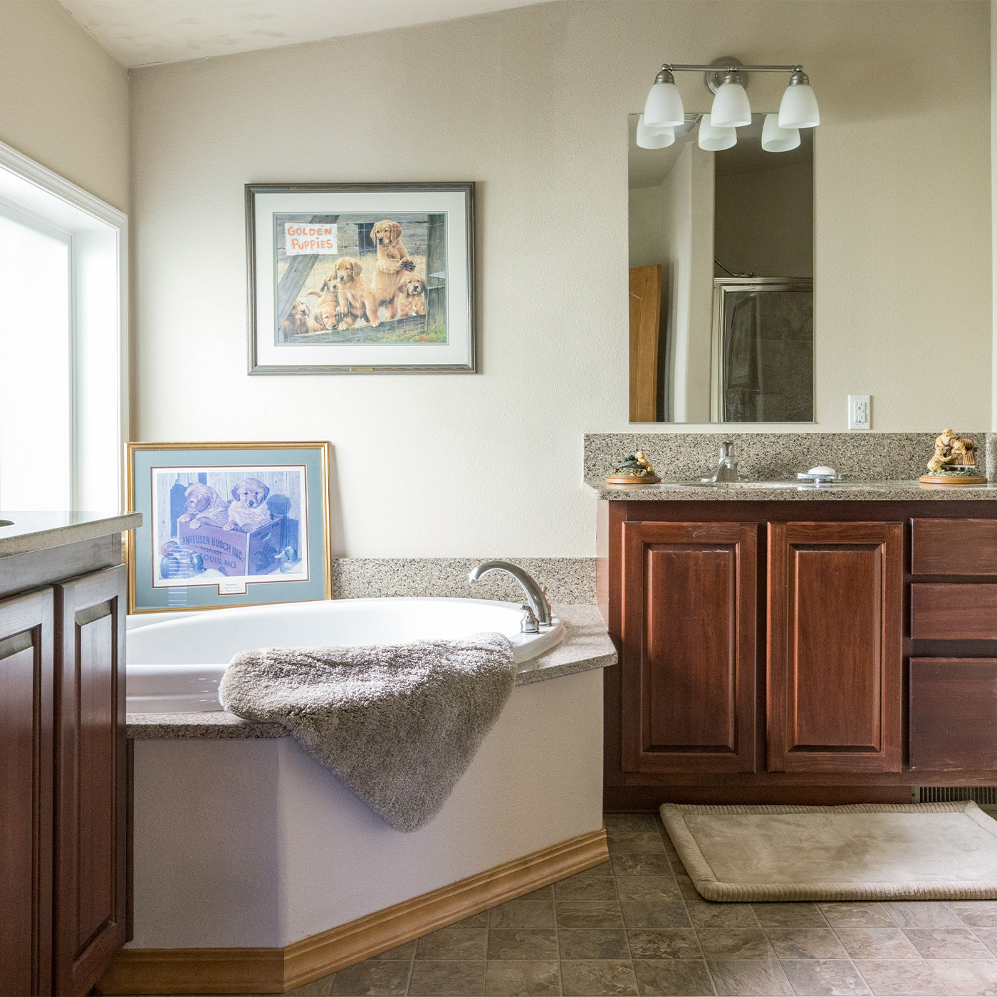 Bathroom with bathtub, vanity, and framed pictures of golden retrievers on the wall